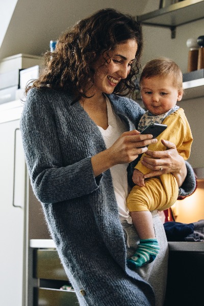 mom holding baby looking at phone